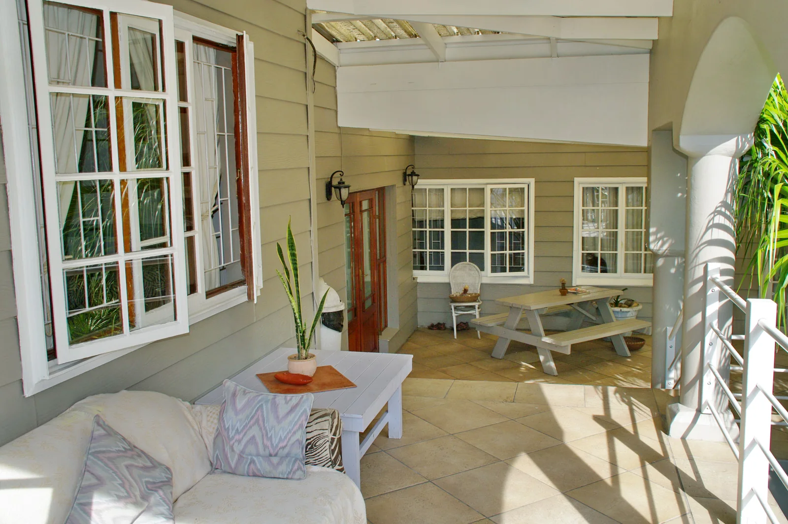 Sunny upstairs veranda with outdoor seating at Knysna N2 Lodge